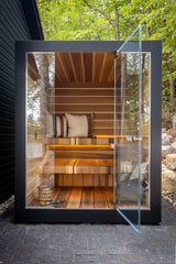 Modern outdoor WellHouse sauna with Riva Striped Interior and custom striped benches with panoramic glass front  in a Muskoka forest setting